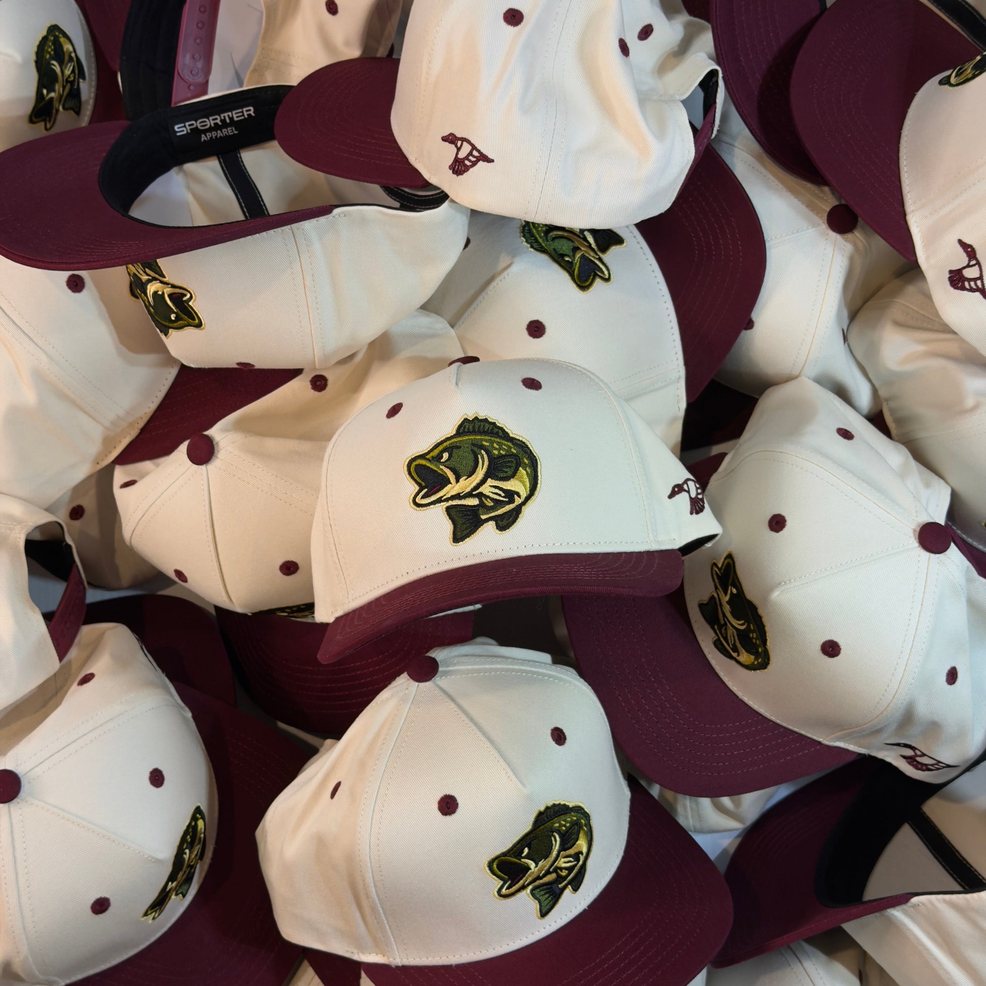 Collection of maroon and white baseball caps with a logo on a table.