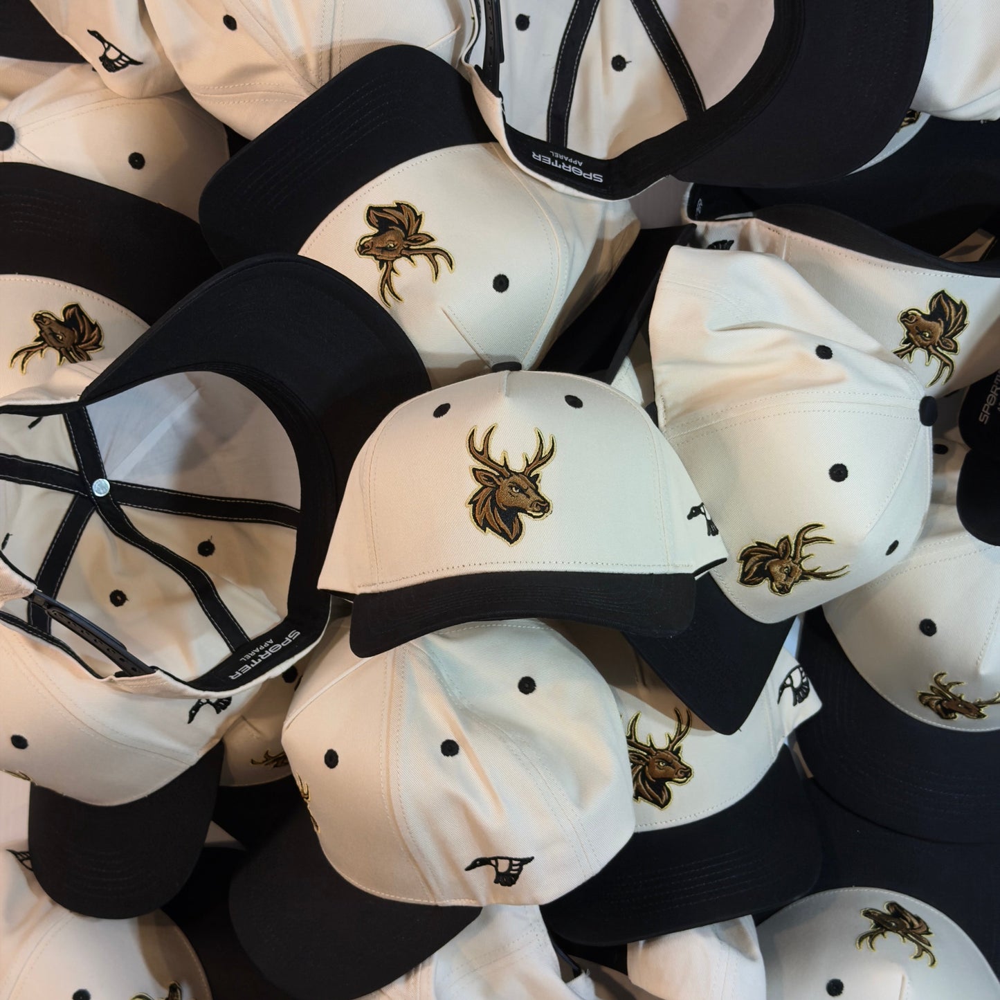 Collection of white and black caps with deer emblem on a black background
